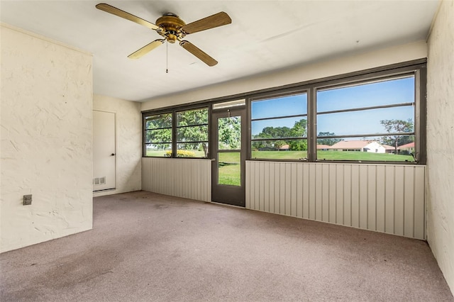 spare room featuring radiator, carpet, a textured wall, visible vents, and a ceiling fan
