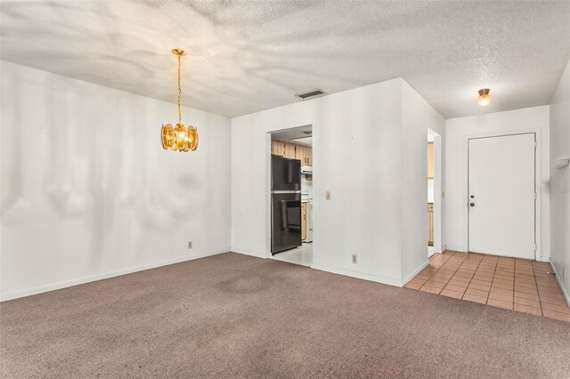 unfurnished room with a textured ceiling, a chandelier, light colored carpet, baseboards, and visible vents