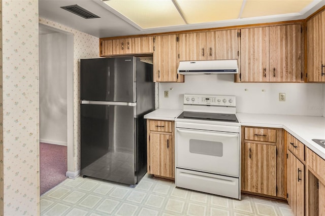 kitchen with white electric range, exhaust hood, light floors, visible vents, and freestanding refrigerator