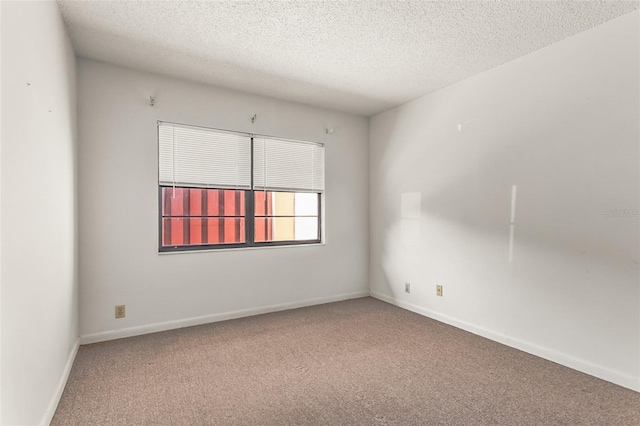 unfurnished room featuring carpet, a textured ceiling, and baseboards
