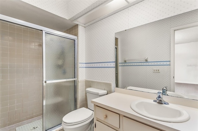 bathroom featuring a shower stall, toilet, vanity, and wallpapered walls