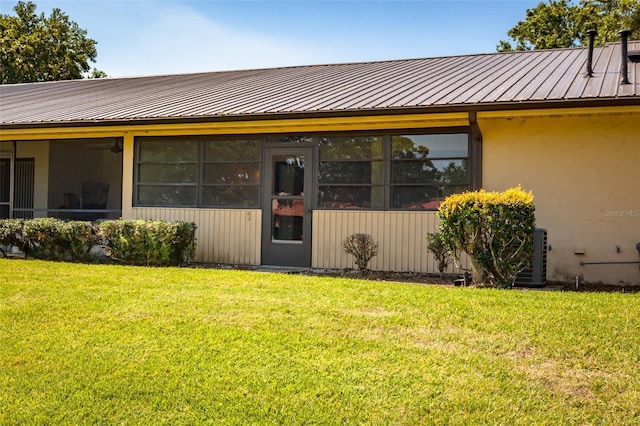 doorway to property featuring a lawn and metal roof