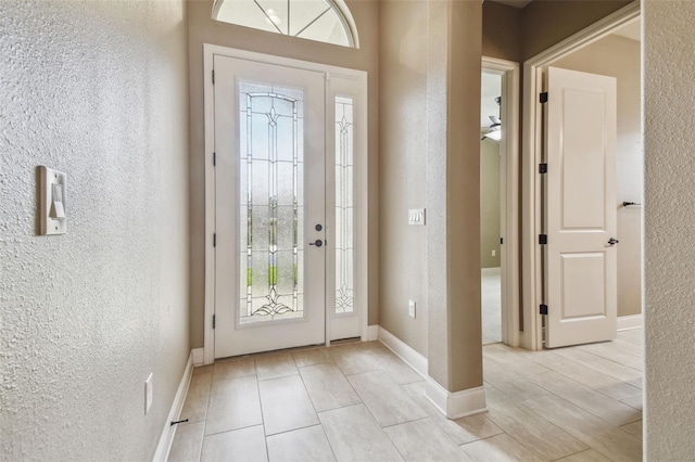foyer with a textured wall and baseboards