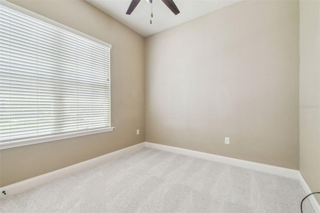 spare room featuring light carpet, baseboards, and ceiling fan