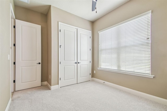 unfurnished bedroom with baseboards, a closet, light colored carpet, and multiple windows