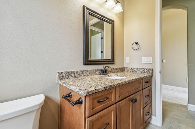 half bath featuring tile patterned floors, vanity, and toilet