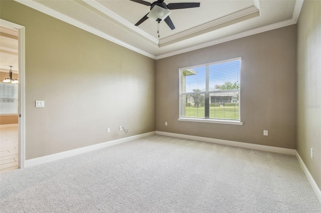 unfurnished room with a tray ceiling, baseboards, light colored carpet, ceiling fan with notable chandelier, and ornamental molding
