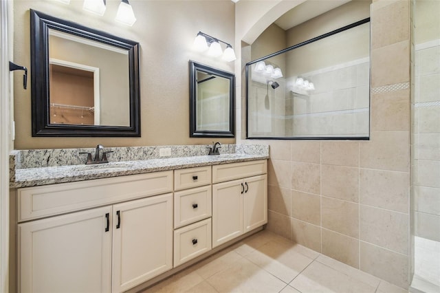 bathroom featuring double vanity, tile patterned flooring, a walk in shower, and a sink