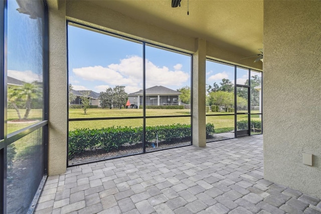 unfurnished sunroom with ceiling fan