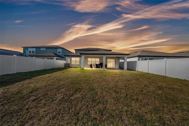 rear view of house featuring a fenced backyard, a yard, and a patio