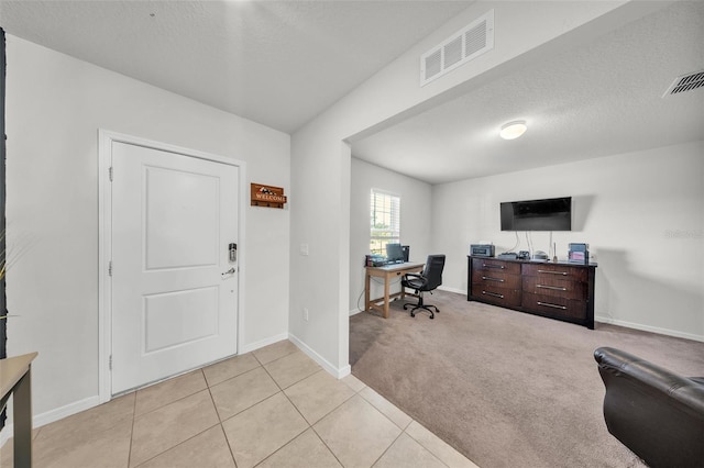 office with light tile patterned flooring, a textured ceiling, visible vents, and baseboards