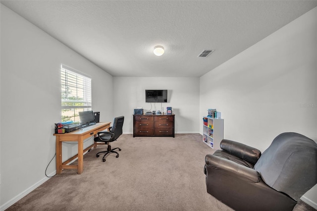 office space with light colored carpet, baseboards, a textured ceiling, and visible vents