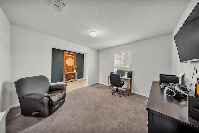 office space with light colored carpet, baseboards, a textured ceiling, and visible vents