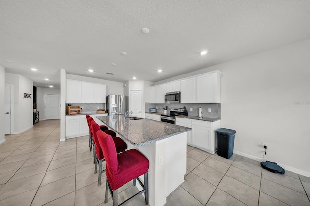 kitchen with a sink, light tile patterned floors, backsplash, baseboards, and appliances with stainless steel finishes