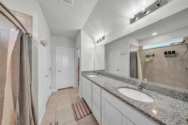 full bath with tile patterned floors, visible vents, a sink, and tiled shower