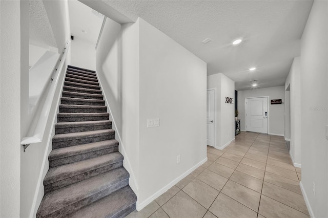 stairway featuring tile patterned floors, baseboards, recessed lighting, and a textured ceiling
