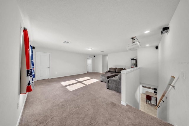 carpeted living area featuring baseboards, visible vents, recessed lighting, and a textured ceiling