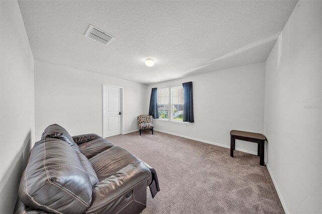 living area featuring baseboards, carpet flooring, a textured ceiling, and visible vents