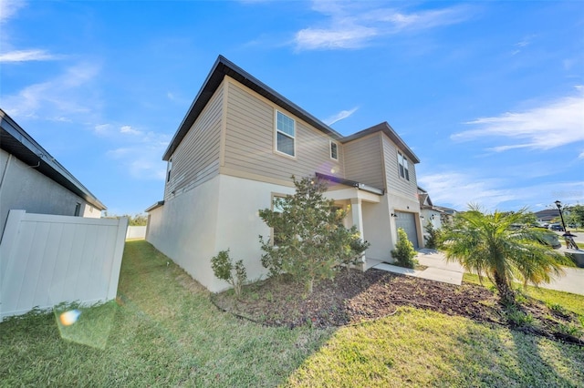 view of home's exterior featuring stucco siding, a lawn, fence, and a garage