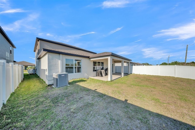 back of house with a fenced backyard, central AC, a lawn, a patio, and stucco siding