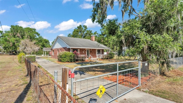 view of front facade featuring a gate, brick siding, a porch, and a fenced front yard