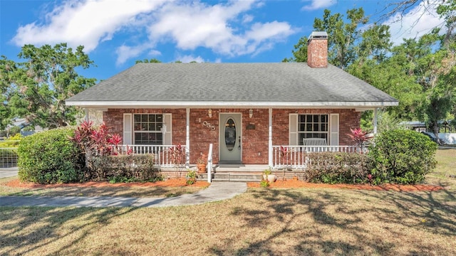 view of front of house featuring a chimney, roof with shingles, and a porch