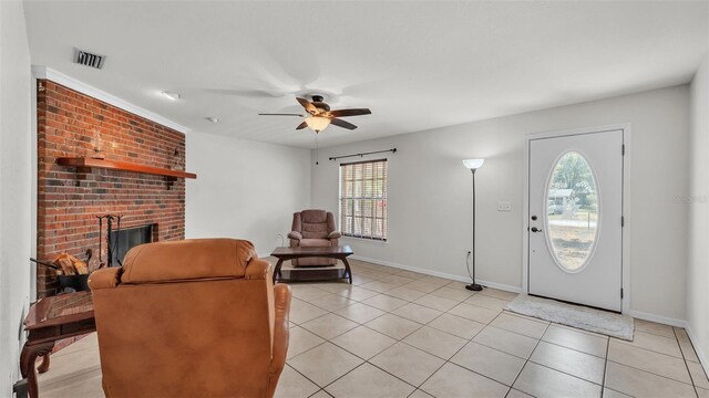 entryway featuring baseboards, visible vents, ceiling fan, a fireplace, and light tile patterned floors