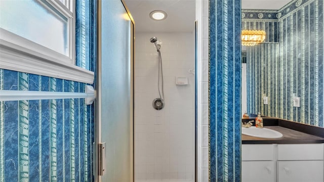 bathroom featuring wallpapered walls, a shower stall, and vanity