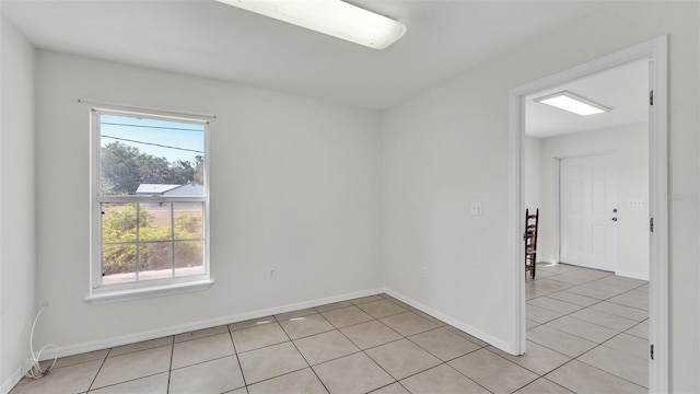 empty room featuring light tile patterned flooring and baseboards
