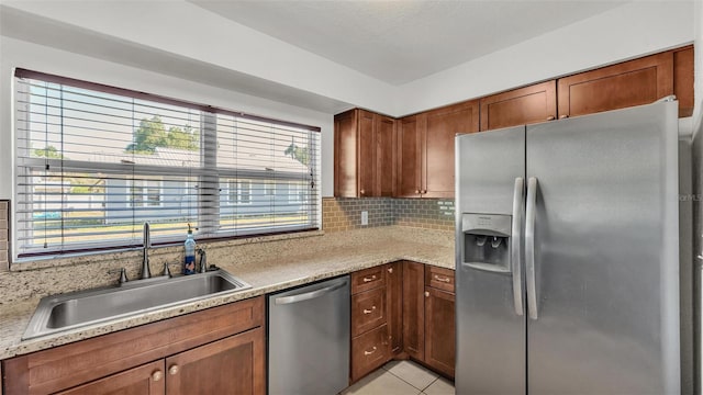 kitchen with stainless steel appliances, light countertops, a sink, and backsplash