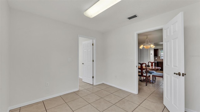empty room featuring a chandelier, visible vents, baseboards, and light tile patterned flooring