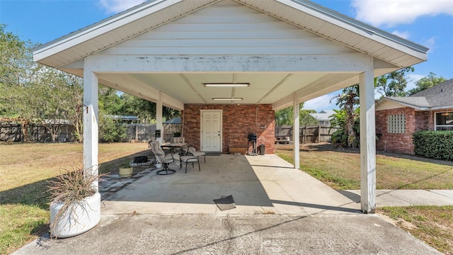 view of patio with concrete driveway, fence, and a carport