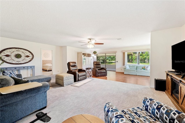 living area featuring a ceiling fan, carpet floors, and a textured ceiling
