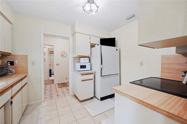 kitchen with light countertops, visible vents, light tile patterned floors, white appliances, and decorative backsplash