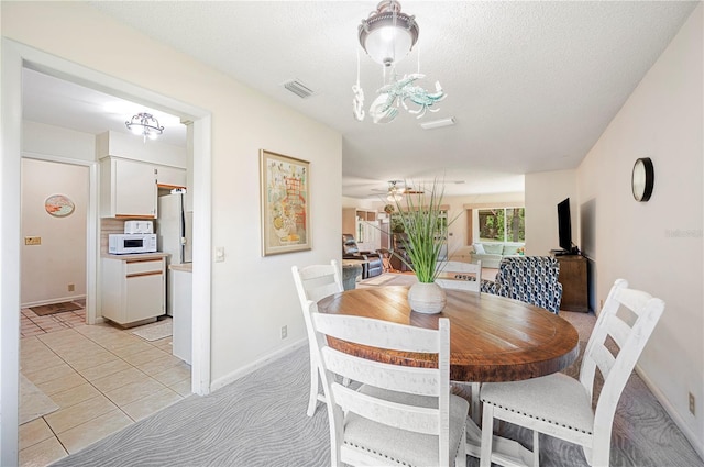 dining area featuring ceiling fan with notable chandelier, baseboards, visible vents, and light tile patterned floors