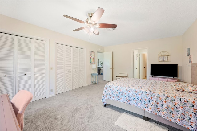 bedroom with two closets, carpet floors, baseboards, and ceiling fan