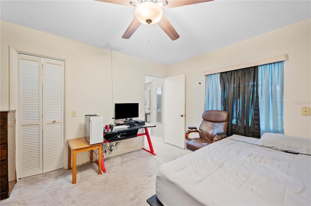 carpeted bedroom featuring a textured ceiling, visible vents, a closet, and ceiling fan