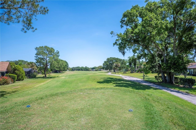 surrounding community with golf course view and a yard