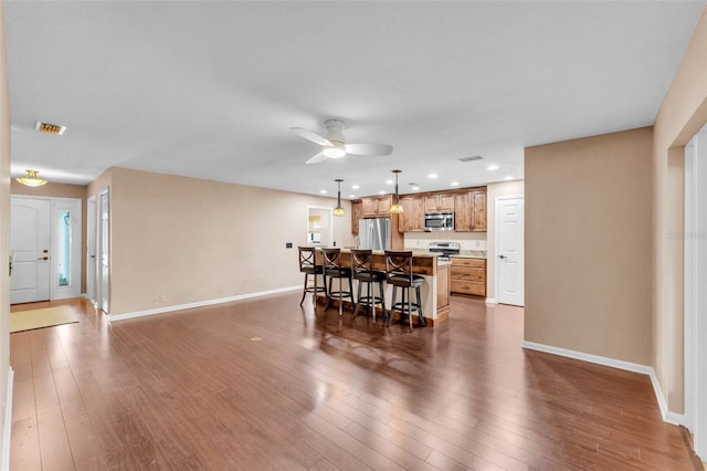 dining room featuring a ceiling fan, baseboards, visible vents, and dark wood-type flooring