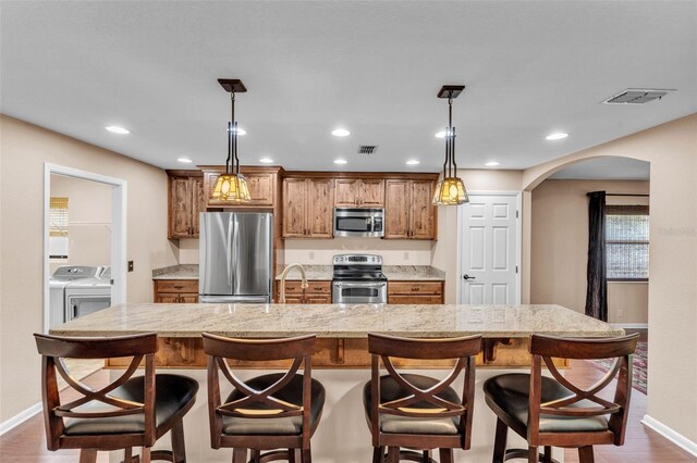 kitchen with washing machine and clothes dryer, arched walkways, baseboards, and appliances with stainless steel finishes