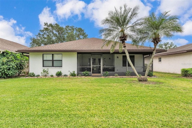 rear view of house with a lawn, stucco siding, and a sunroom