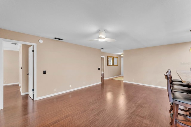 unfurnished living room with ceiling fan, visible vents, baseboards, and wood finished floors
