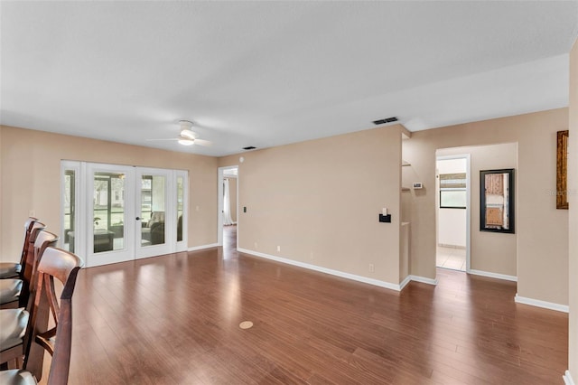 unfurnished living room featuring ceiling fan, french doors, visible vents, wood finished floors, and baseboards