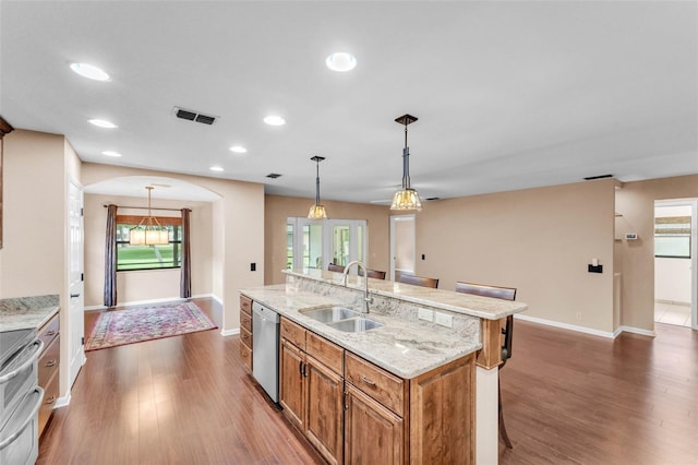kitchen with a kitchen bar, visible vents, appliances with stainless steel finishes, arched walkways, and a sink