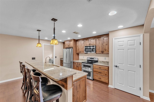 kitchen with a breakfast bar area, stainless steel appliances, a sink, and light wood-style flooring