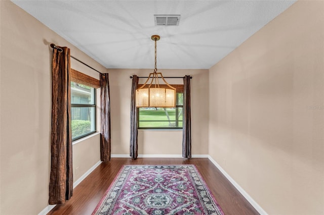 doorway to outside featuring baseboards, dark wood-type flooring, and visible vents