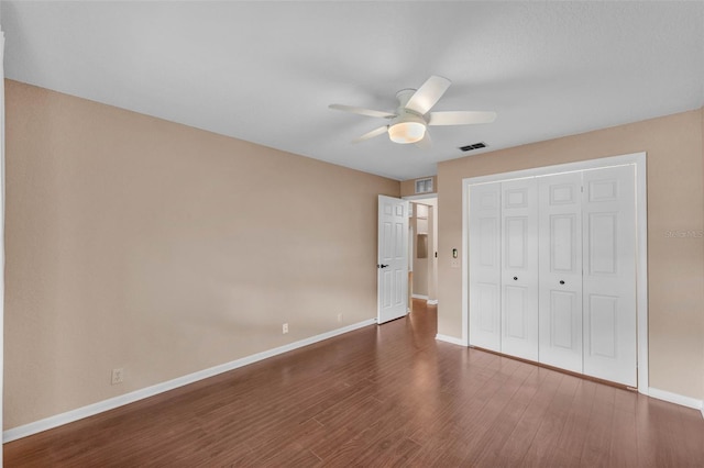 unfurnished bedroom with a ceiling fan, baseboards, wood finished floors, visible vents, and a closet