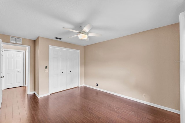 unfurnished bedroom with visible vents, dark wood-style flooring, and baseboards