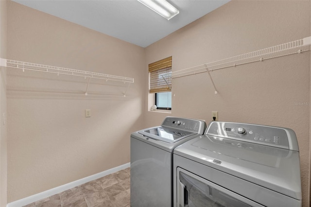clothes washing area featuring baseboards, laundry area, and washer and dryer