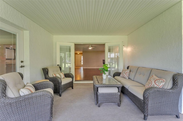 living room featuring a textured wall, light colored carpet, and wooden ceiling
